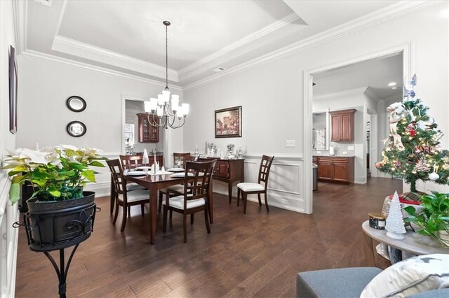 dining area featuring a tray ceiling, dark wood-type flooring, and a notable chandelier