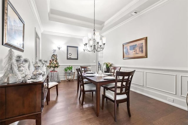 dining space featuring a tray ceiling, dark hardwood / wood-style flooring, ornamental molding, and an inviting chandelier