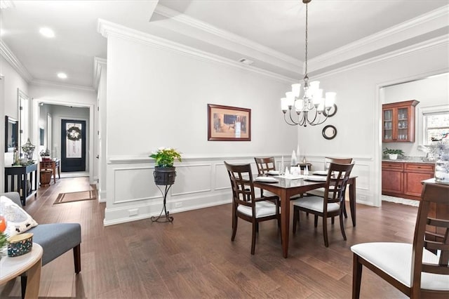 dining room featuring a raised ceiling, an inviting chandelier, crown molding, and dark wood-type flooring