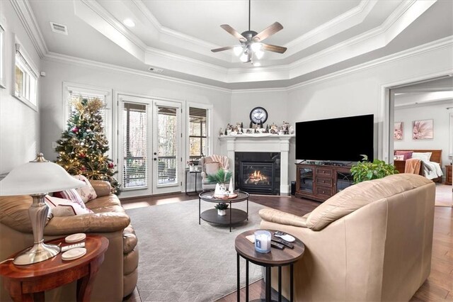 living room featuring french doors, ornamental molding, a raised ceiling, ceiling fan, and hardwood / wood-style floors