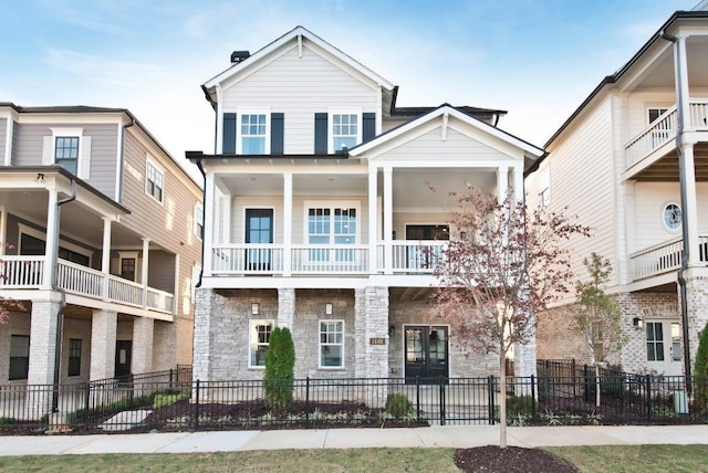 view of front of property with a balcony, fence private yard, and stone siding