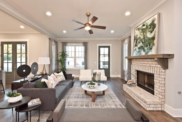 living room with crown molding, dark wood-style flooring, ceiling fan, and a fireplace