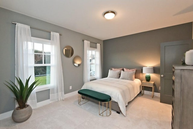 bedroom featuring baseboards, multiple windows, and light carpet