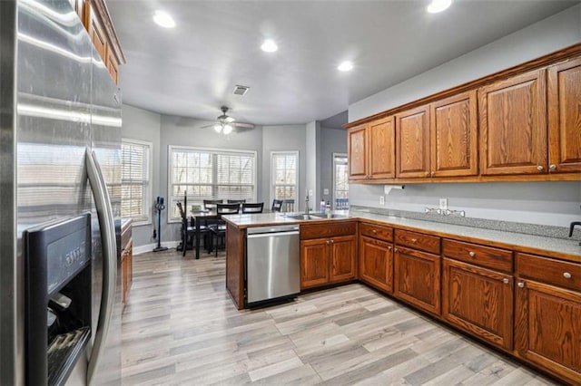 kitchen featuring a sink, a ceiling fan, light countertops, appliances with stainless steel finishes, and brown cabinets