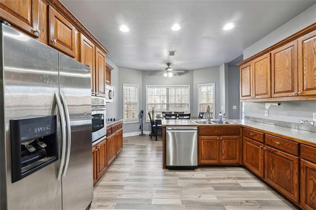 kitchen with appliances with stainless steel finishes, brown cabinetry, a sink, and visible vents