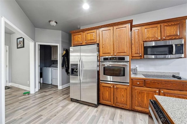 kitchen with brown cabinetry, washer and clothes dryer, light wood-style flooring, appliances with stainless steel finishes, and light countertops