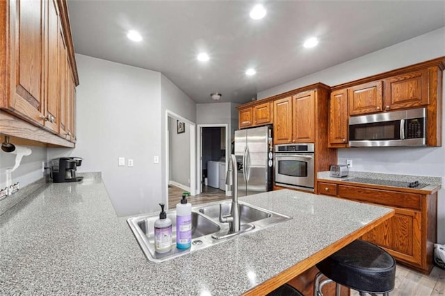 kitchen featuring a breakfast bar area, recessed lighting, light countertops, appliances with stainless steel finishes, and brown cabinetry