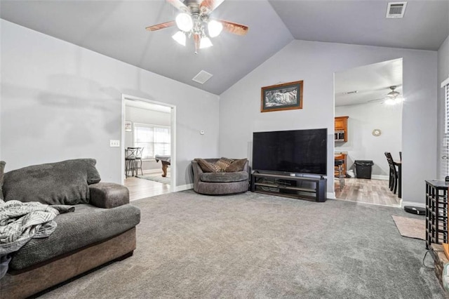 carpeted living area featuring lofted ceiling, baseboards, visible vents, and a ceiling fan