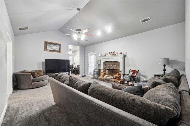 carpeted living area with lofted ceiling, visible vents, a ceiling fan, and a stone fireplace