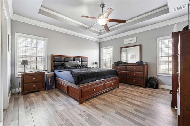 bedroom with light wood-style flooring, visible vents, and a raised ceiling