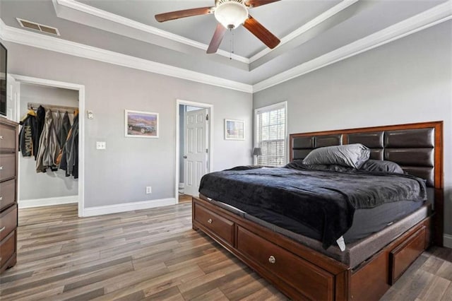 bedroom featuring visible vents, a tray ceiling, and wood finished floors