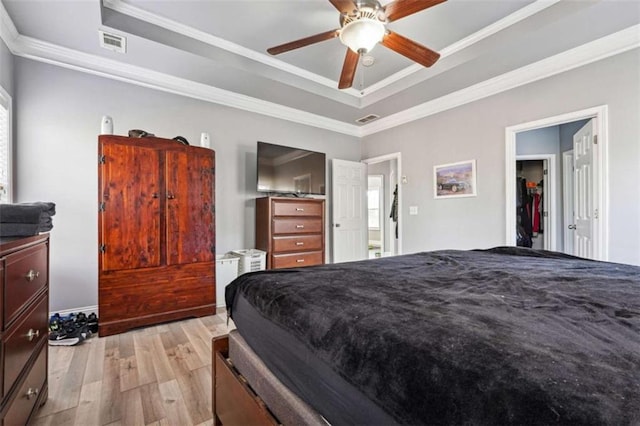 bedroom featuring a raised ceiling, visible vents, crown molding, and light wood finished floors