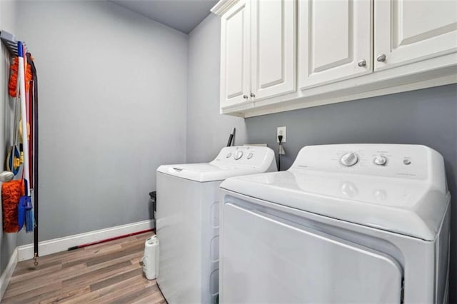 clothes washing area with light wood-type flooring, cabinet space, baseboards, and washer and dryer