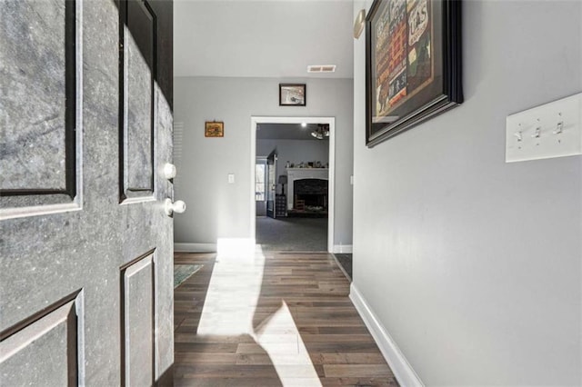 hallway with visible vents, baseboards, and dark wood finished floors