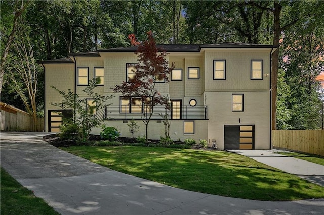 view of front facade with fence, concrete driveway, a front yard, an attached garage, and brick siding