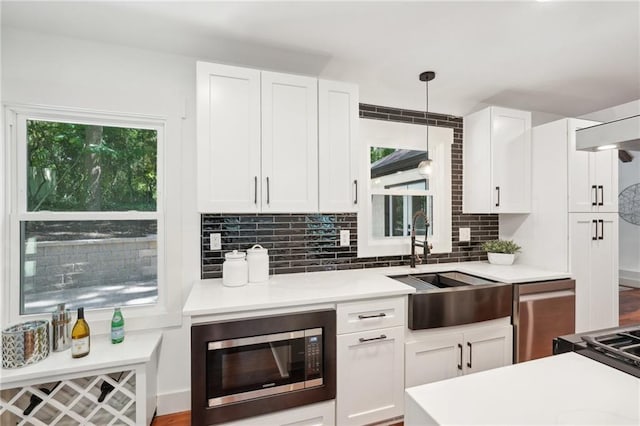 kitchen with a wealth of natural light, a sink, tasteful backsplash, stainless steel appliances, and white cabinets