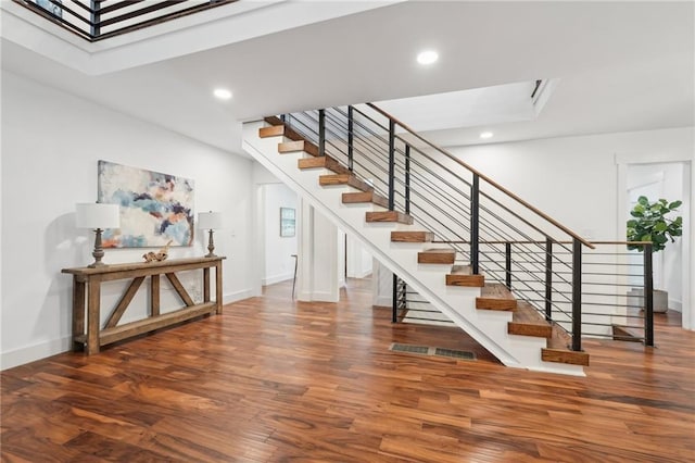 stairs featuring a skylight, recessed lighting, wood finished floors, and baseboards