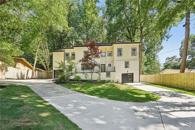 townhome / multi-family property featuring an attached garage, concrete driveway, a front yard, and fence