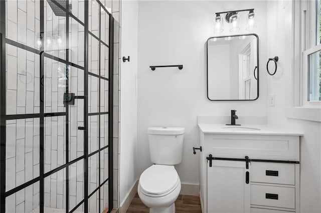 full bathroom with vanity, wood finished floors, baseboards, a walk in shower, and toilet