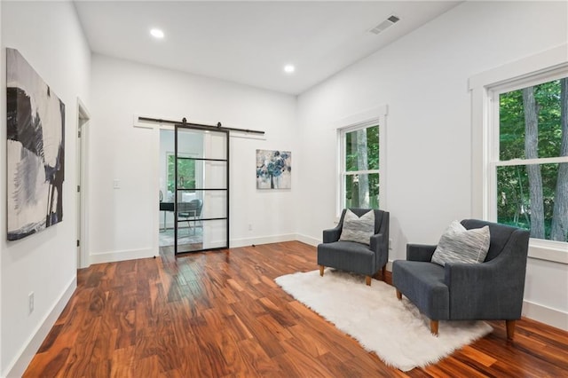 sitting room featuring visible vents, baseboards, a barn door, recessed lighting, and wood finished floors