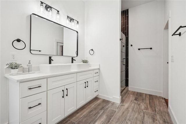 full bath with vanity, wood finished floors, baseboards, and a stall shower