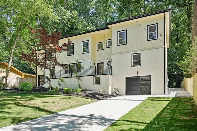 view of front of property with an attached garage, concrete driveway, a front yard, and fence