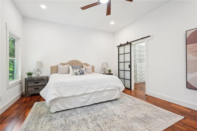 bedroom featuring recessed lighting, baseboards, dark wood-type flooring, and a barn door