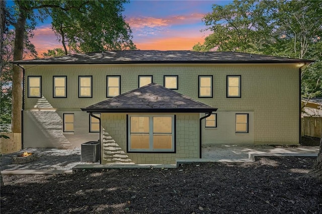 rear view of house featuring a patio, fence, an outdoor fire pit, roof with shingles, and central AC unit