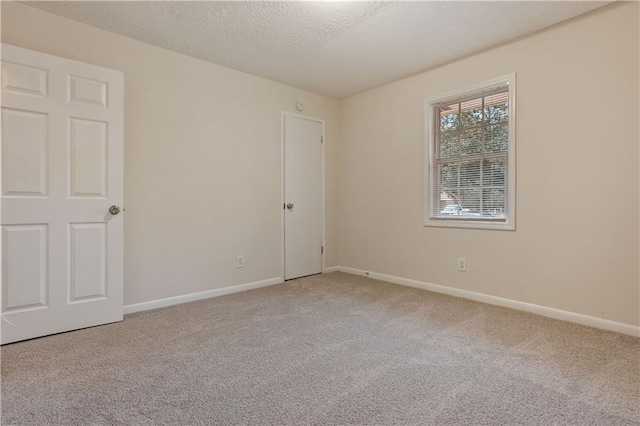 carpeted empty room with a textured ceiling