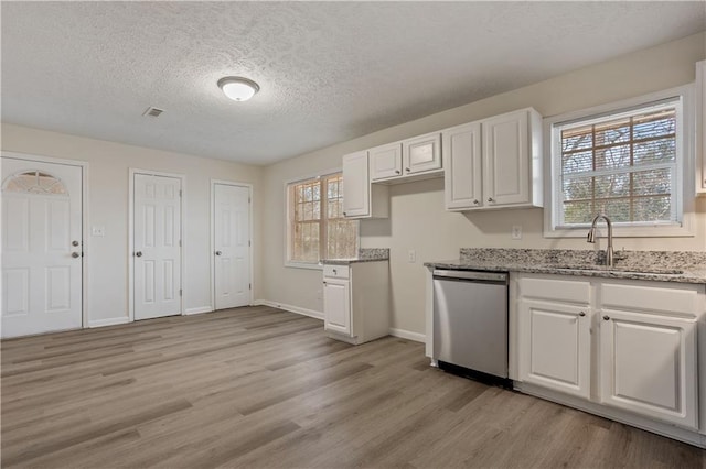 kitchen with light stone countertops, dishwasher, white cabinetry, sink, and light wood-type flooring