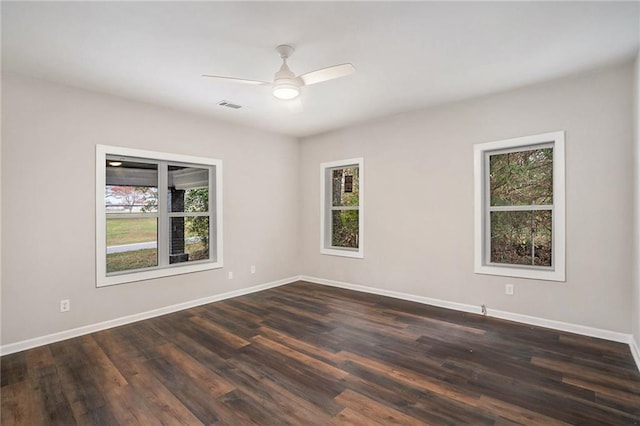 empty room with dark hardwood / wood-style flooring, a wealth of natural light, and ceiling fan