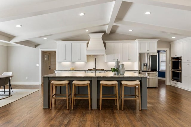 kitchen with a kitchen breakfast bar, appliances with stainless steel finishes, an island with sink, and custom range hood