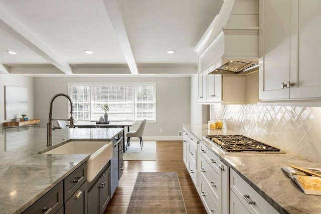 kitchen featuring beamed ceiling, a sink, stainless steel appliances, decorative backsplash, and dark wood-style flooring