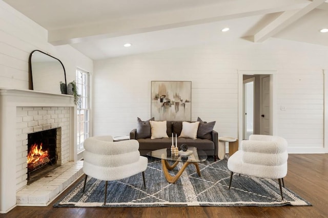 living room with lofted ceiling with beams, a brick fireplace, wood finished floors, and recessed lighting