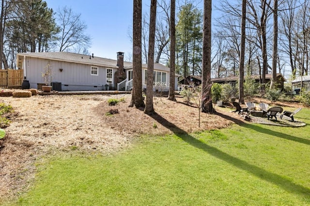 rear view of property featuring a fire pit, fence, a chimney, a yard, and crawl space