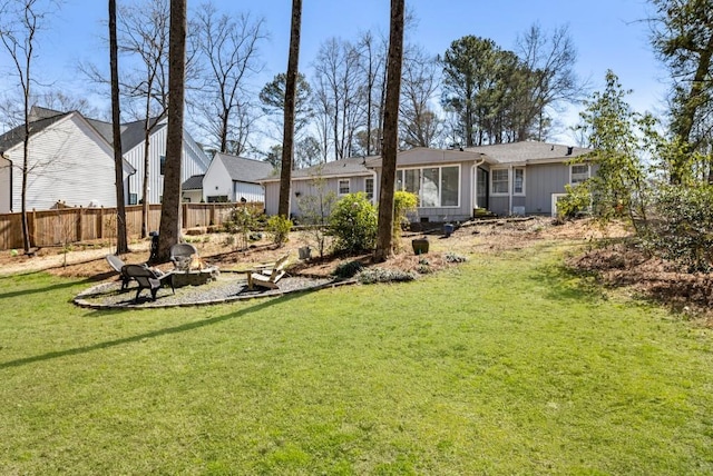 view of yard with a fire pit, fence, and a sunroom