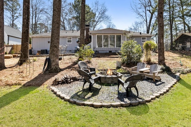 back of property with an outdoor fire pit, a yard, central AC, a chimney, and crawl space