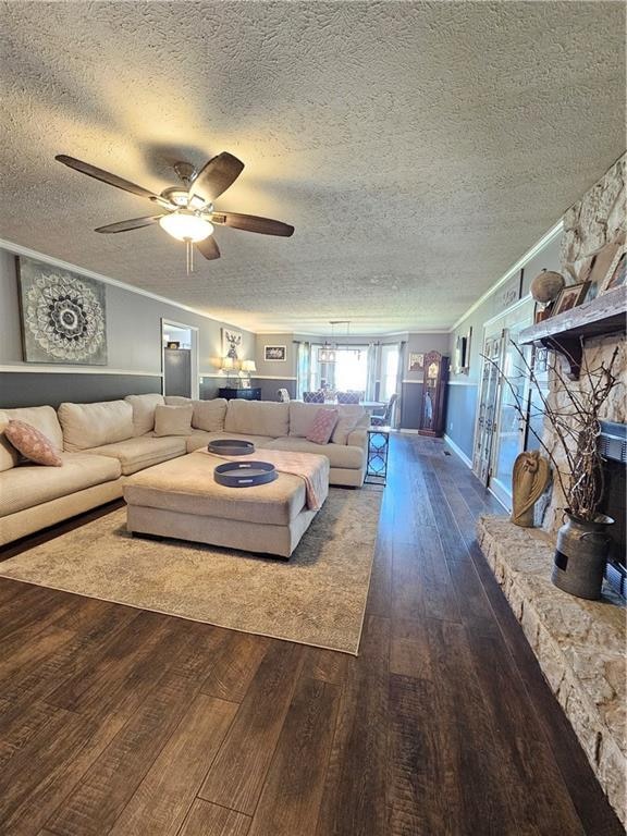 living room featuring ceiling fan, crown molding, a textured ceiling, and dark hardwood / wood-style flooring