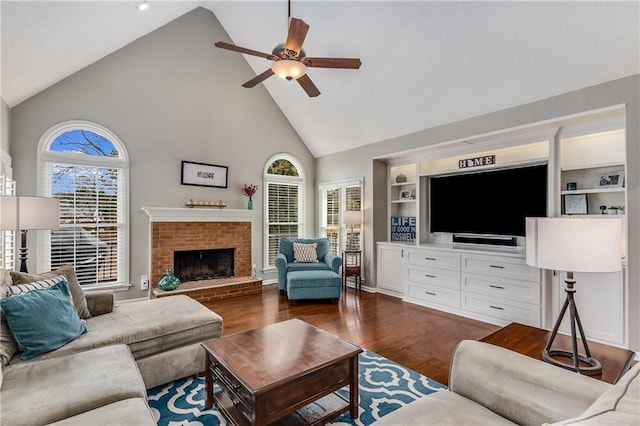 living room with a brick fireplace, dark wood finished floors, a ceiling fan, and a healthy amount of sunlight