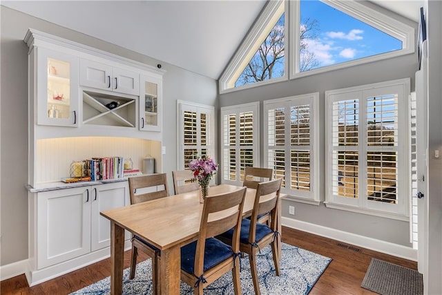 dining area featuring visible vents, baseboards, vaulted ceiling, and dark wood-style flooring