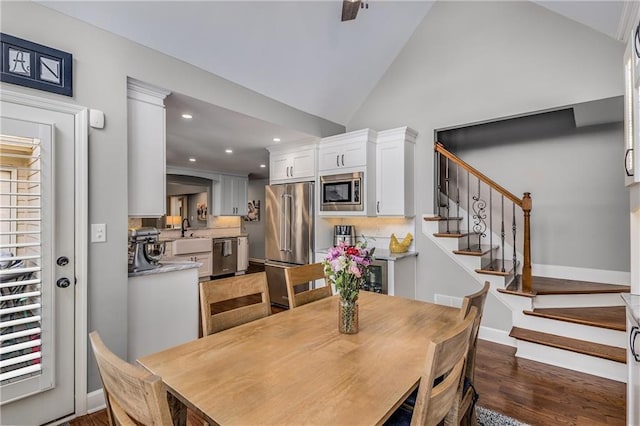 dining room featuring dark wood-style floors, recessed lighting, high vaulted ceiling, baseboards, and stairs