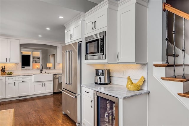 kitchen featuring appliances with stainless steel finishes, wine cooler, white cabinetry, and a sink