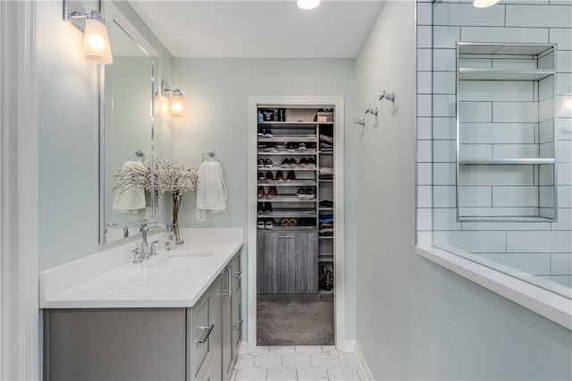 bathroom with baseboards, a walk in closet, and vanity