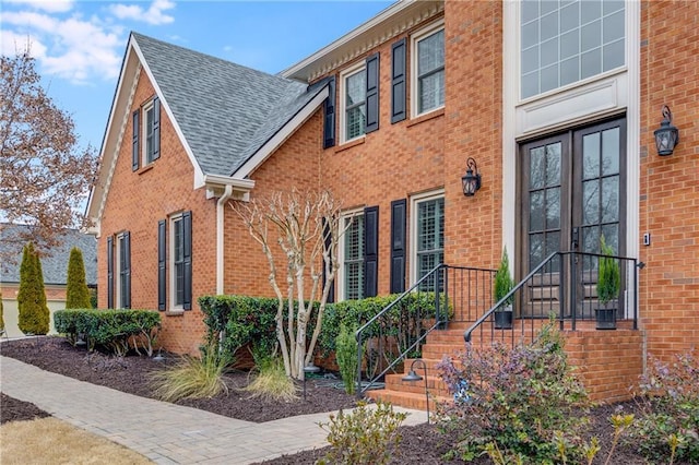 view of front of property featuring a shingled roof, french doors, and brick siding