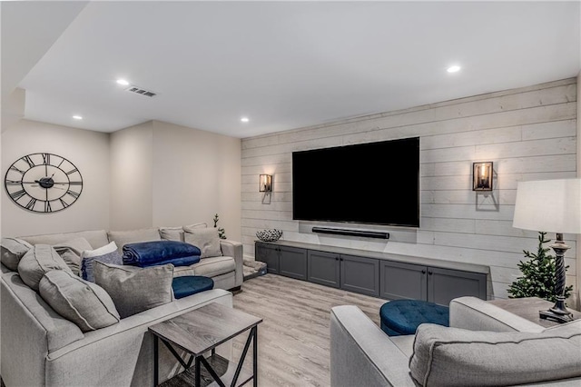 living area with wooden walls, recessed lighting, visible vents, and light wood-style floors