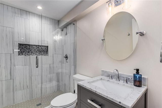 bathroom featuring vanity, a shower stall, and toilet