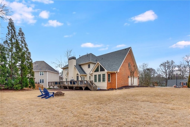 rear view of house with brick siding, a wooden deck, a fire pit, and a yard