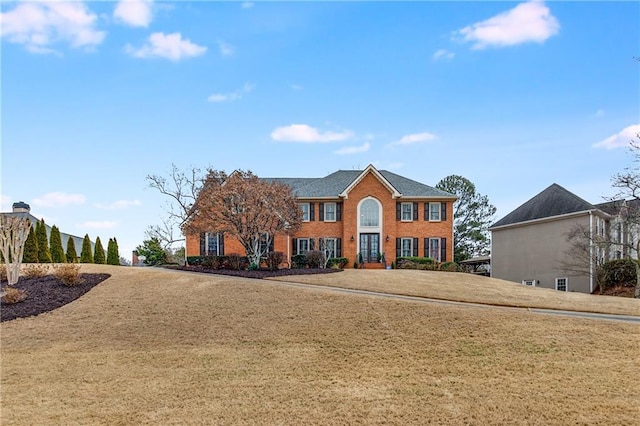 colonial house with a front lawn and brick siding