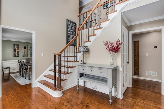 staircase featuring baseboards, visible vents, wood finished floors, and ornamental molding