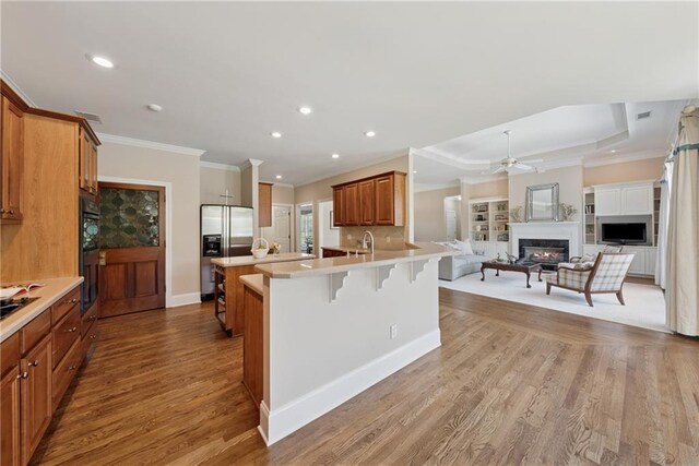 4790 Hyde Rd, Cumming, GA 30040 - kitchen featuring crown molding, a ceiling fan, black appliances, a warm lit fireplace, and a breakfast bar
